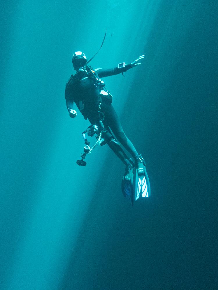 Female scuba diving with rays of light behind her