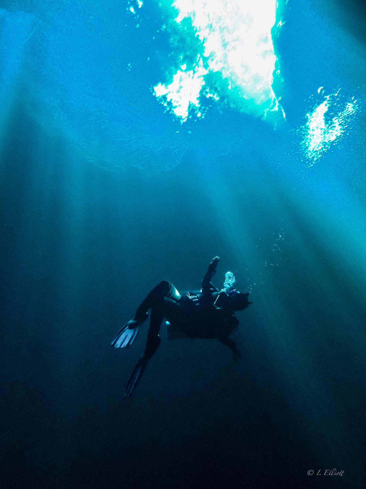 Female scuba diving looking up into a hole